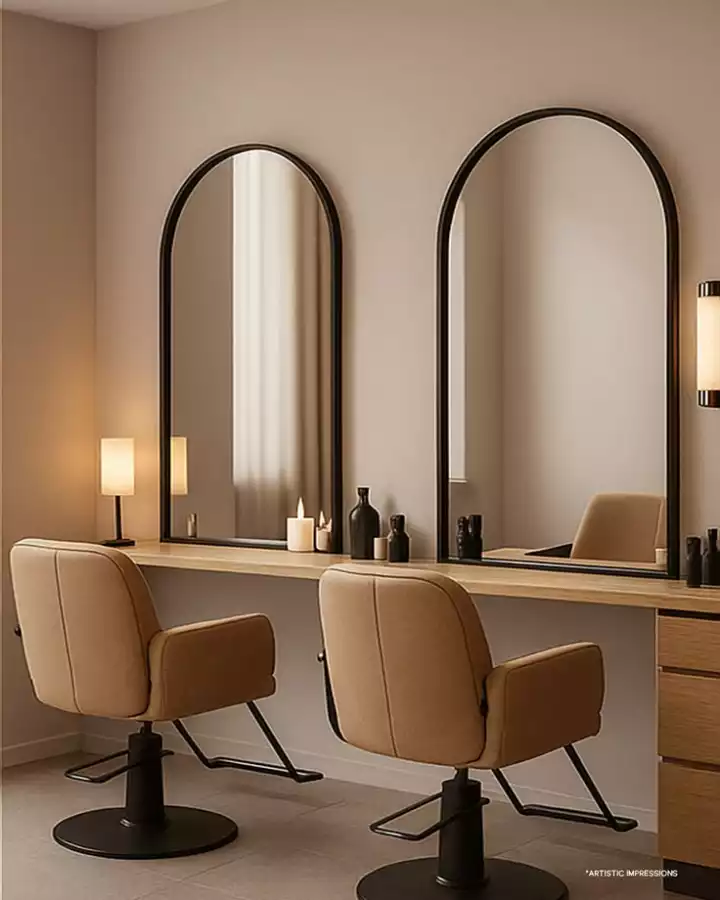 a hair salon with mirrors and chairs in front of the counter top, two lamps on either side of the mirror