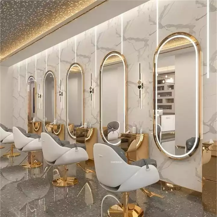 the interior of a hair salon with gold accents and mirrors on the wall, along with white chairs