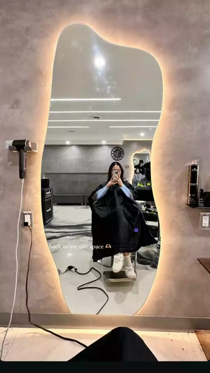 a woman sitting in front of a large mirror